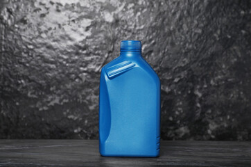 Motor oil in blue canister on black table near dark wall