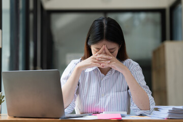 Stressed Asian business woman worry with many document on desk at office
