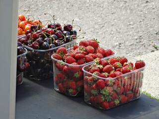 Close-up of strawberries, nuts, dried fruits, cherries, medlar in plastic cups. Counter with fruits, berries and dried fruits