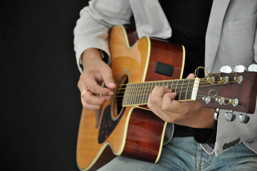Fototapeta na wymiar guitarist playing acoustic guitar on black background(selective focus).