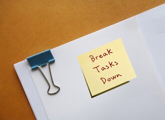 Office document with handwritten text note Break Tasks Down - means to break down tasks into...