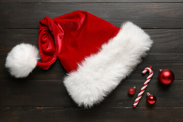 Obraz na płótnie Canvas Santa hat with Christmas decorations on dark wooden background