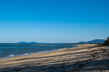 Cowley beach, Cassowary Coast, Queensland, Australia. Long afternoon shadows across the sand with mountains and ocean on the horizon.