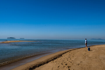 Person fishing on Cowley Beach, Cassowary Coast, Queensland, Australia. There is a vast expanse of beach, ocean and horizon