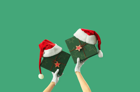 Woman With Christmas Gift Boxes And Santa Hats On Green Background