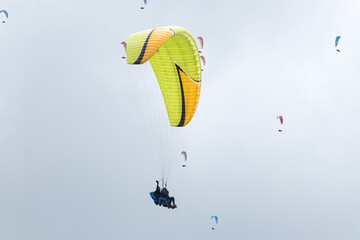 A paraglider flight in a blue sky with clouds, paragliding competition