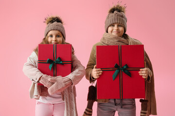 Little children with Christmas presents on pink background