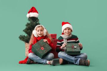 Little children with presents and Christmas tree sitting on green background