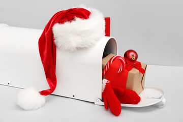 Mailbox with Santa hat, mittens, Christmas gift and decor on grey background