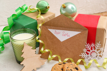 Letter to Santa with glass of milk, cookies, presents and Christmas decor on white background