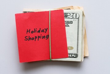 Cash Dollars money and red note with text written HOLIDAY SHOPPING , concept of setting limit budget for holiday spending