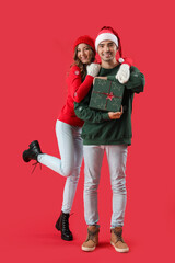 Young couple in love with Christmas gift on red background