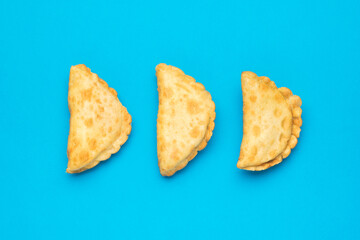 Three meat pies on a light blue background.