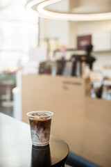 Ice coffee on a plastic cup with cream being poured into it showing the texture