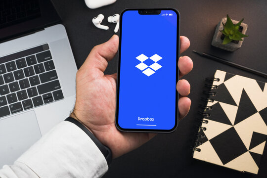 Man holding a smartphone with Dropbox cloud storage app on the screen on black background table. Office environment. Rio de Janeiro, RJ, Brazil. November 2022
