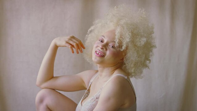 Studio shot of confident and positive young albino woman wearing underwear laughing and smiling - shot in slow motion