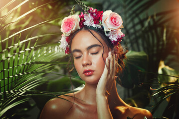 Face, forest and beauty with flower headband in tropical plants outdoors bokeh background. Woman,...