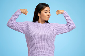 Woman raising arms showing biceps as metaphor of female power and independence