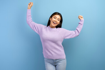 Happy excited female standing with clenched fists, celebrating victory and her success
