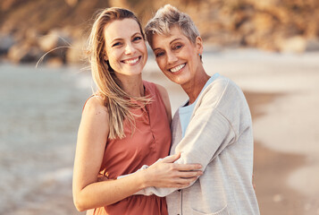 Women, mom and daughter hug on beach enjoy nature and family time together on the shore with smile. Love, water and portrait of woman hugging senior mother on happy ocean holiday and walk on sea sand