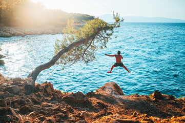 Man Jumping to the water of blue Mediterranean Sea. Active Summer vacation in Croatia. Photo full of Energy, Edit space