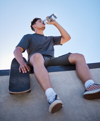 Skateboard, young man and drinking water bottle, relax and on break on sunny day outdoor. Male,...