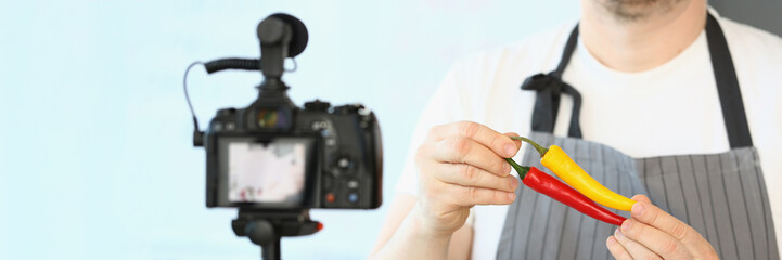 Male chef in apron showing chillies pepper on camera