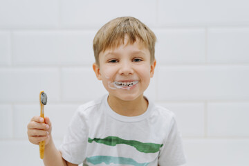 cute 5 years old boy brushing teeth with bamboo tooth brush in bathroom. Image with selective focus