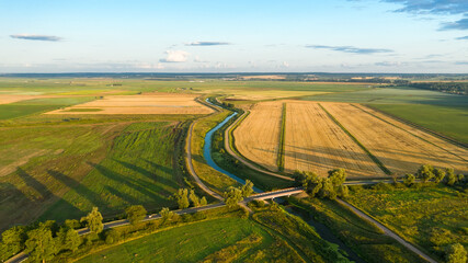 Top view of the countryside, agricultural fields, river and road bridge across the river