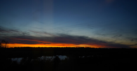 Panorama Sunset with clouds, in orange and colorful shades,World Environment Day concept: Fiery orange sunset sky with dark clouds.