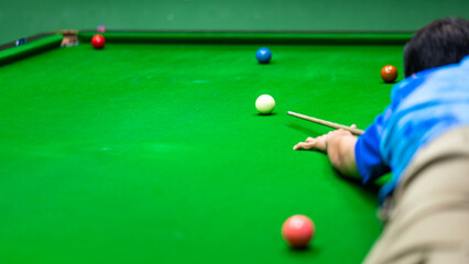 Action of a human is aiming to hitting the white snooker ball. Playing snooker activity photo,...