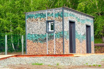 the room of a public toilet in the park, the walls of which consist of stones and large glass stones. the concept of recycling and the use of recyclables.