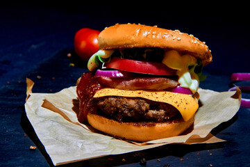 Big beef burger on baking paper with cheese full of fresh vegetable