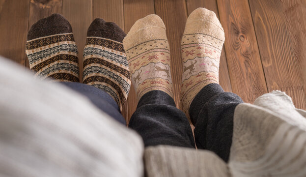 couple with woolen socks sitting on wooden floor, winter cosy scene