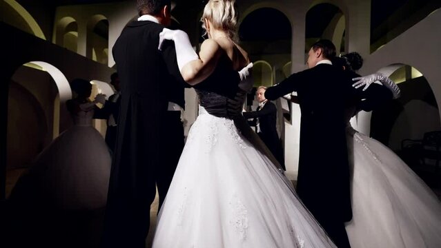 beautiful ladies and gentlemen are dancing waltz in prom in ballroom, gorgeous dresses and suits