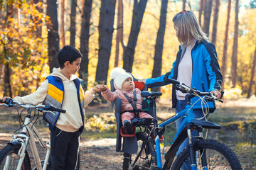 Obraz premium children with mom ride a bike oneautumn day in a pine forest