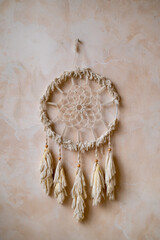 round dreamcatcher woven from threads hangs on the wall