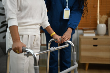 Female caregiver assisting elderly woman to walk with frame. Elderly healthcare and Home health care service concept
