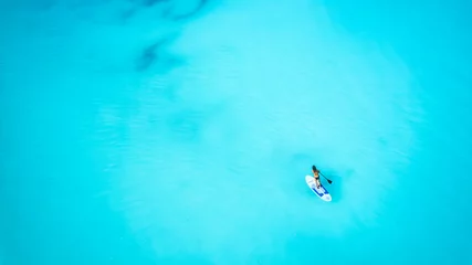 Foto op Plexiglas Aerial top down view of a woman on a stand up paddle (SUP) board over the turquoise Caribbean ocean in the Bahamas islands © moofushi