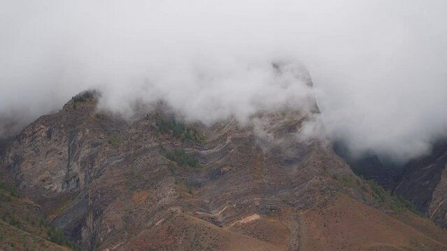 4K shot of fog around the mountain peaks during the stormy weather at Tandi in Lahaul Spiti district at Himachal Pradesh, India. Clouds rolling over the peaks of the mountain. Nature background.	