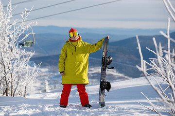 Woman snowboarder poses with board.