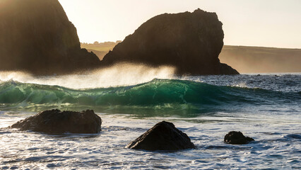 Majestic landscape image of jade turquoise waves crashing onto shore and rocks in Kynance Cove...