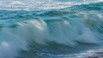 Fototapeta Large Powerful jade turquoise colored waves crashing at Sennen Cove in Cornwall during late sunset obraz