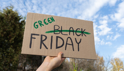 Hand holding sign Green Black Friday, word Black crossed out. Protester with placard at zero waste...