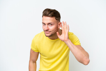 Young blonde caucasian man isolated on white background listening to something by putting hand on the ear