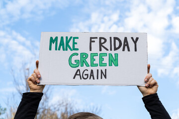 Woman holding sign with slogan Make Friday Green Again. Protester with placard at zero waste...