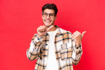 Fototapeta premium Young caucasian handsome man isolated on red background pointing to the side to present a product