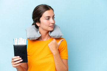 Naklejka premium Young beautiful woman with Inflatable travel Pillow isolated on blue background pointing to the side to present a product