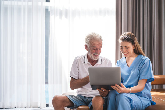 Asian nurse or caregiver teaching senior Caucasian man to handle with digital laptop computer at home