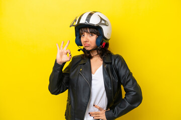 Young latin woman with a motorcycle helmet isolated on yellow background